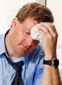 Photo: Man in suit, sweating and wiping head with cloth.